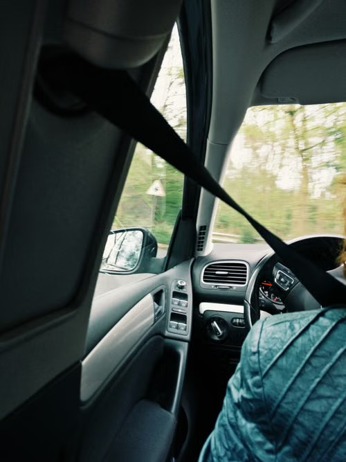 View from a passenger seat along a road, with the seatbelt crossing the frame