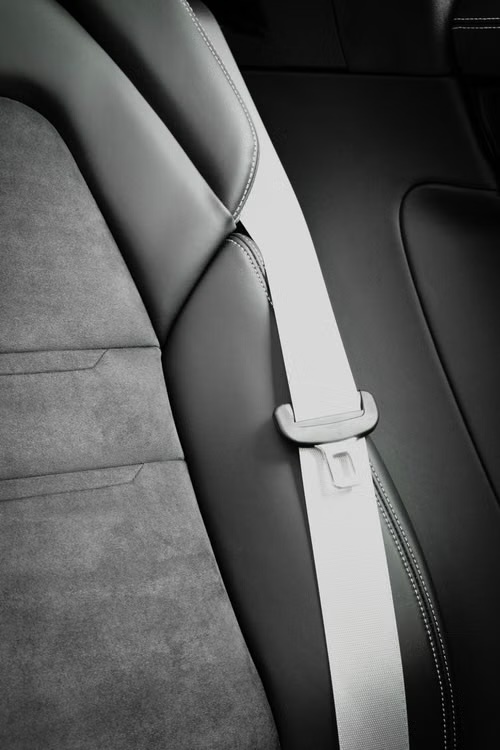 A light grey retractable seatbelt drawn diagonally across a dark vehicle seat